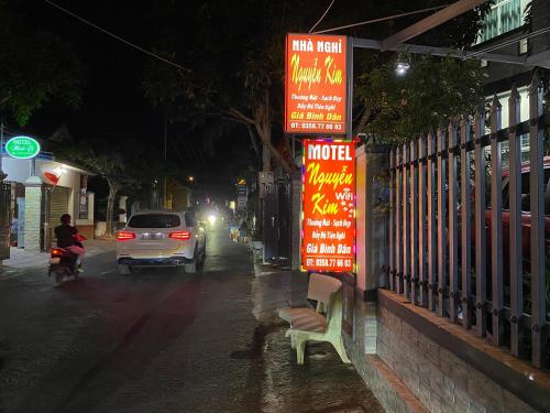 a car driving down a street at night with neon signs at Nguyễn Kim Motel in Long Hai