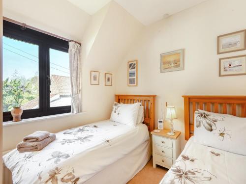 two beds in a bedroom with a window at Langford Cottage in Ringstead