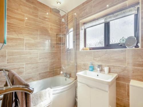 a bathroom with a tub and a toilet and a sink at Langford Cottage in Ringstead
