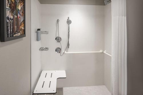 a white bathroom with a bench and a shower at Courtyard by Marriott New Orleans Metairie in Metairie