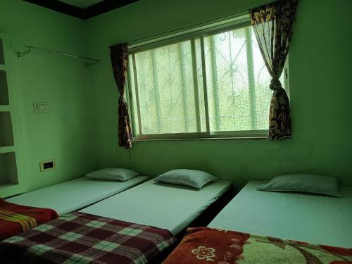 2 camas en una habitación verde con ventana en MONIKA MANSION Bodhgaya, en Bodh Gaya