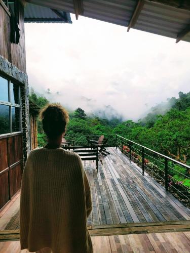 a person standing on a deck looking out at the mountains at Hotel Rivel - Restaurant & Nature Retreat in Turrialba