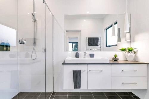 a white bathroom with a sink and a shower at Platinum on Washpool in Wellington East