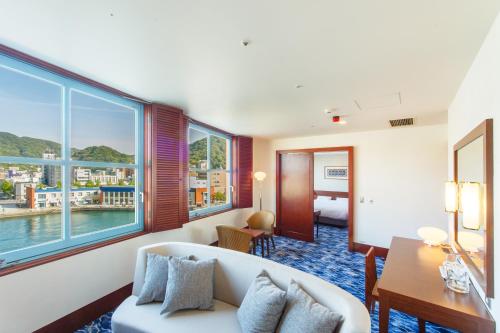 a hotel room with a couch and a room with a view at Premier Hotel Mojiko in Kitakyushu
