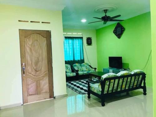 - un salon avec des murs verts et une porte en bois dans l'établissement GREENS HOMESTAY, à Sungai Besar