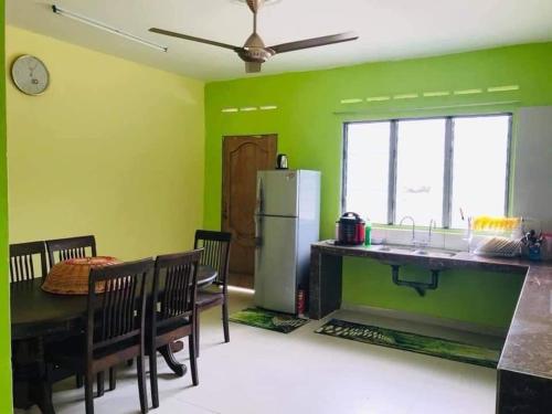 une cuisine et une salle à manger aux murs verts dans l'établissement GREENS HOMESTAY, à Sungai Besar