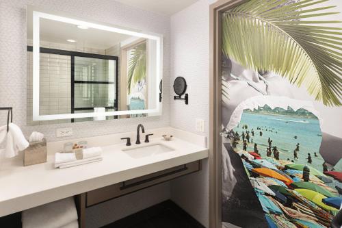 Renaissance Fort Lauderdale West Hotel في بلانتايشن: حمام مع حوض ومرآة كبيرة