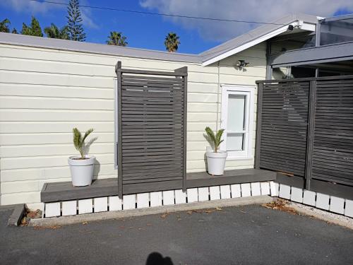 two potted plants sitting on a patio in front of a house at Adorable Beach Unit Stanmore Bay in Whangaparaoa