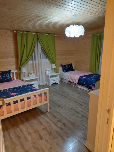 2 camas en una habitación con cortinas verdes en Cabana Oprișor, en Ocna Sibiului
