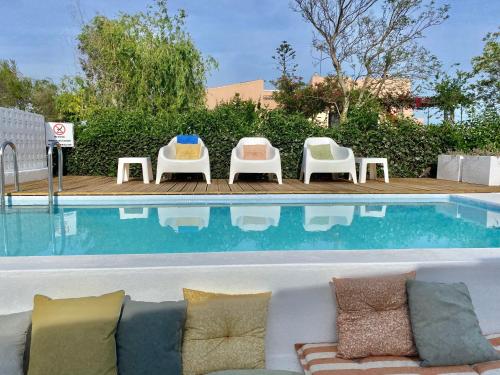 - un canapé et des chaises à côté de la piscine dans l'établissement Casa Pedra Rosa - VINHAS de NEXE, à Faro