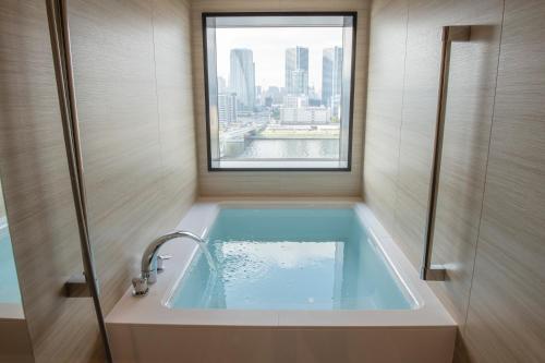 a bathroom with a bath tub with a window at La Vista Tokyo Bay in Tokyo