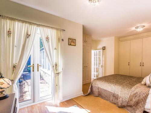 a bedroom with a bed and a large window at Kennel Cottage in Alwinton