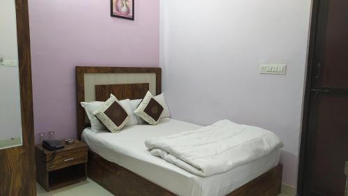 a bedroom with a bed with white sheets and pillows at Hotel Greenoz in Jaipur