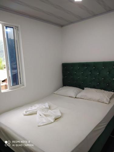 Cama blanca con cabecero negro y ventana en Apartamentos Olaya!, en Bahía Solano