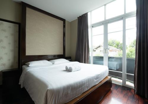 Greenview Ekkamai10 Suite في بانكوك: غرفة نوم بسرير ونافذة كبيرة