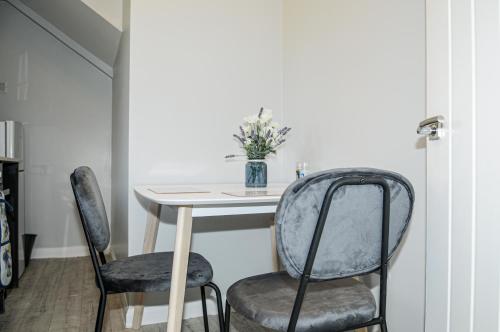 a dining room table with two chairs and a vase of flowers at Greater London, 1 Bed London Flat, Parking, nr Metro Stations, 15mins to London in London
