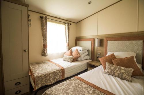 a small bedroom with two beds and a window at Beautiful Caravan With Stunning Sea Views At Haven Hopton Ref 80001h in Great Yarmouth