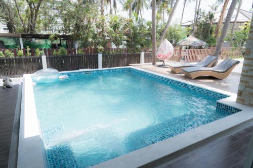 une piscine avec deux chaises longues et une piscine dans l'établissement Nirvana Hua Hin Pool Villa, à Phetchaburi