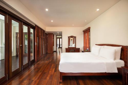 a bedroom with a large white bed and wooden floors at Daisy Beachfront Near Downtown Da Nang in Danang