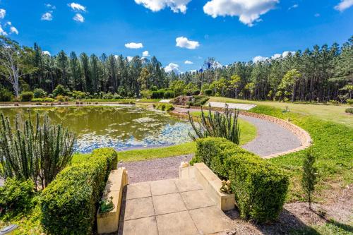 un jardín con un estanque y árboles en el fondo en Standown Park Caravan retreat en Goomboorian