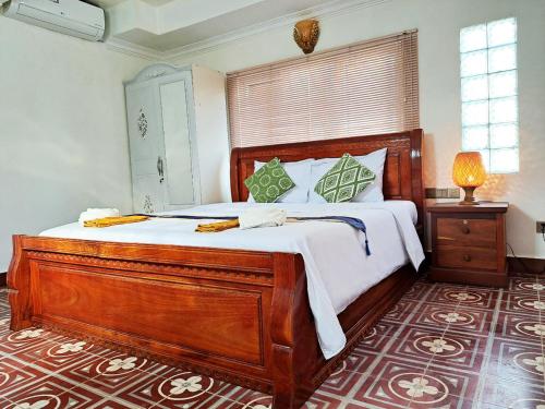 um quarto com uma grande cama de madeira com lençóis brancos em Nary Apartment em Siem Reap