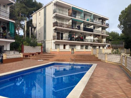 a hotel with a swimming pool in front of a building at APARTAMENTO 10 MIN SITGES in Puigmoltó