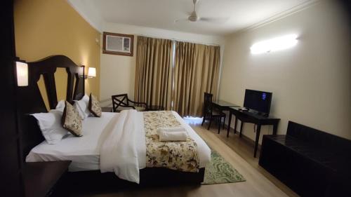 a hotel room with a bed and a desk at Aloha Apartments by blissful Ganges in Rishīkesh