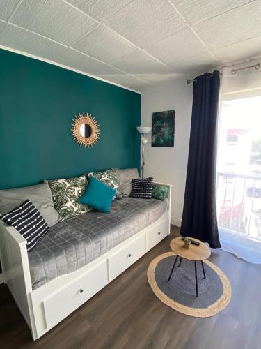 - un canapé dans une pièce dotée d'un mur vert dans l'établissement Studio Le Pharo Résidence avec piscine, au Cap d'Agde