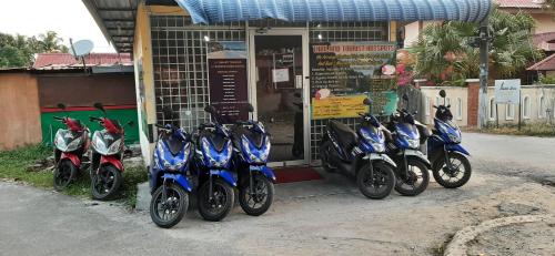 una fila di motociclette parcheggiate di fronte a un negozio di AA Backpackers Hostel a Pantai Cenang