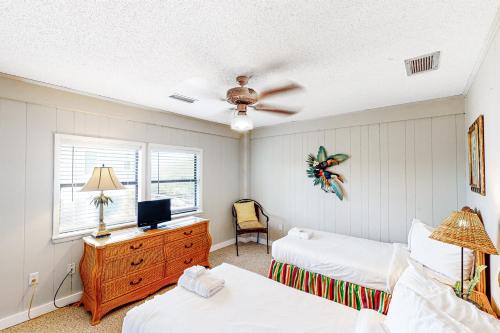 a bedroom with two beds and a desk with a television at Knot Too Shabby in St. George Island