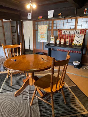 una mesa de madera y 2 sillas en una habitación en 楽園晩御飯(rakuyenbangohan), en Yame