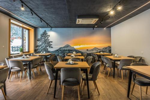 een restaurant met tafels en stoelen en een schilderij aan de muur bij OSW Pan Tadeusz in Krynica Zdrój