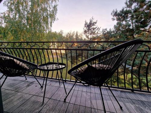 two chairs and a table on a wooden deck at Pirties Spa namas in Molėtai