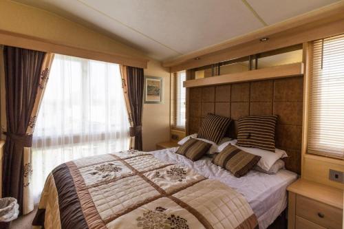 a bedroom with a large bed and a window at Luxury Caravan For Hire At Hopton Holiday Park With Full Sea Views Ref 80010h in Great Yarmouth
