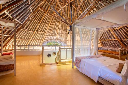 a bedroom with a bed and a straw roof at Aestus Villas Resort in Diani Beach