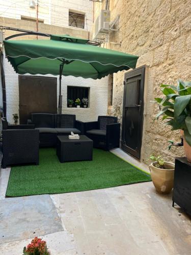 a patio with chairs and a green umbrella at Qandeel - Dar Botto in Bethlehem