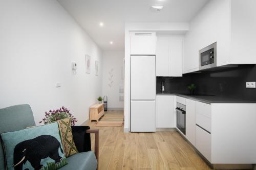 cocina con armarios blancos y encimera negra en Apartamentos La Gringa Centro Gijon II Nueva construcción con posibilidad de Parking en Gijón