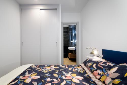 una camera da letto con un letto con copriletto floreale di Apartamentos La Gringa Centro Gijon II Obra nueva con posibilidad de Parking a Gijón