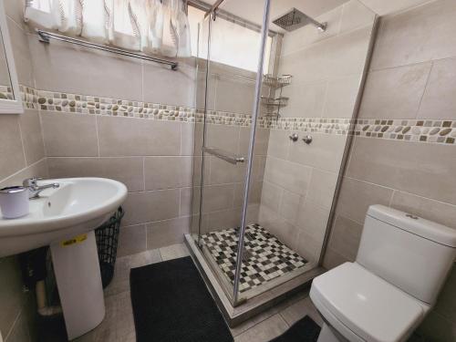 uma casa de banho com um chuveiro, um WC e um lavatório. em Santana 804 Beachfront Apartment with spectacular sea views em Margate