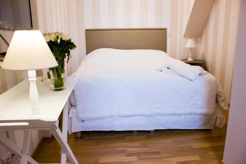 1 dormitorio con cama blanca y mesa con lámpara en Lequatorze, en Compiègne