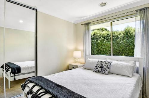 ein weißes Schlafzimmer mit einem Bett und einem Fenster in der Unterkunft Maple Rose Bowral in Bowral