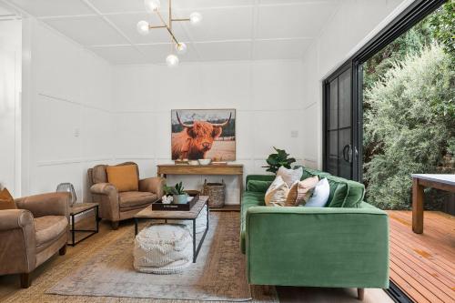 a living room with a green couch and chairs at Bryony Cottage Berrima in Berrima