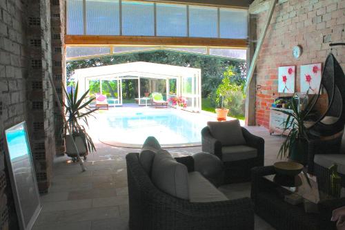 - un salon avec une piscine dans une maison dans l'établissement La Ferme de Bellune, à Mazères