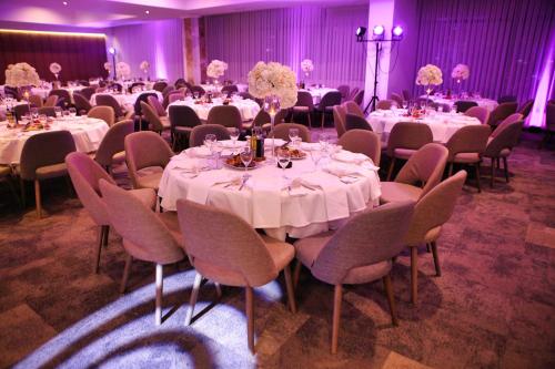 a banquet hall with tables and chairs with white tablecloths at Oaza Hotel in Štip
