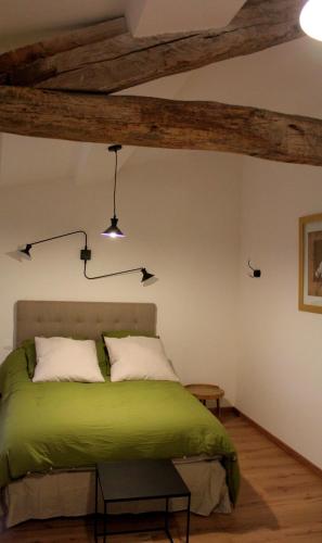 a bedroom with a green bed and wooden beams at La Ferme de Bellune in Mazères