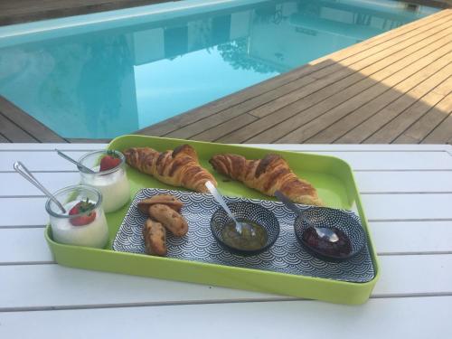ein Tablett mit Essen auf einem Tisch neben einem Pool in der Unterkunft Chambre studio indépendante au calme vue sur piscine in Teyran