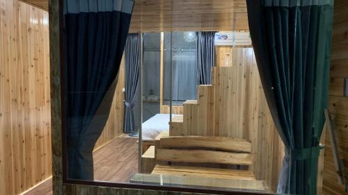 a room with wooden walls and blue curtains and a staircase at Nobita Homestay bắc hà in Bắc Hà