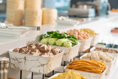a buffet with several bowls of food on a counter at Holiday Inn Express Qingdao Northern West Coast by IHG in Qingdao