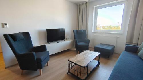 a living room with two chairs and a flat screen tv at Stellaria apartment in Poprad