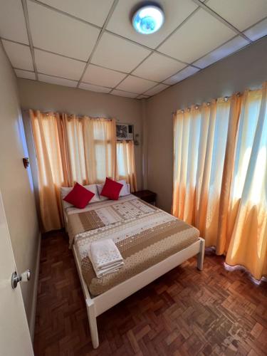 ダバオシティにあるGolden Belle Apartelle and Suitesのベッドルーム1室(赤い枕のベッド1台付)